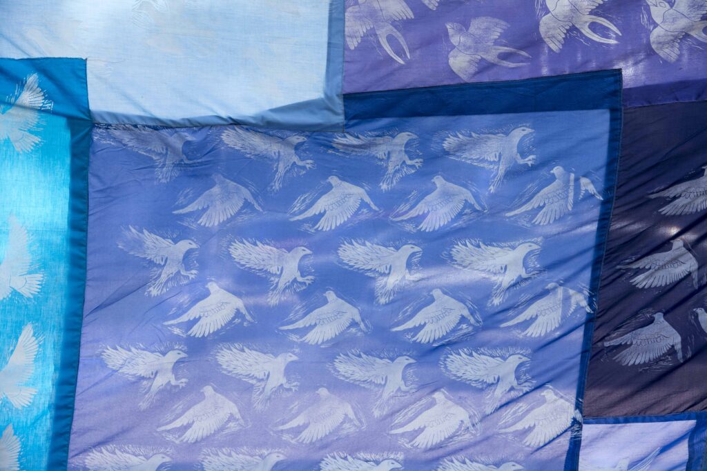 A section of a quilt with screen printed birds. 